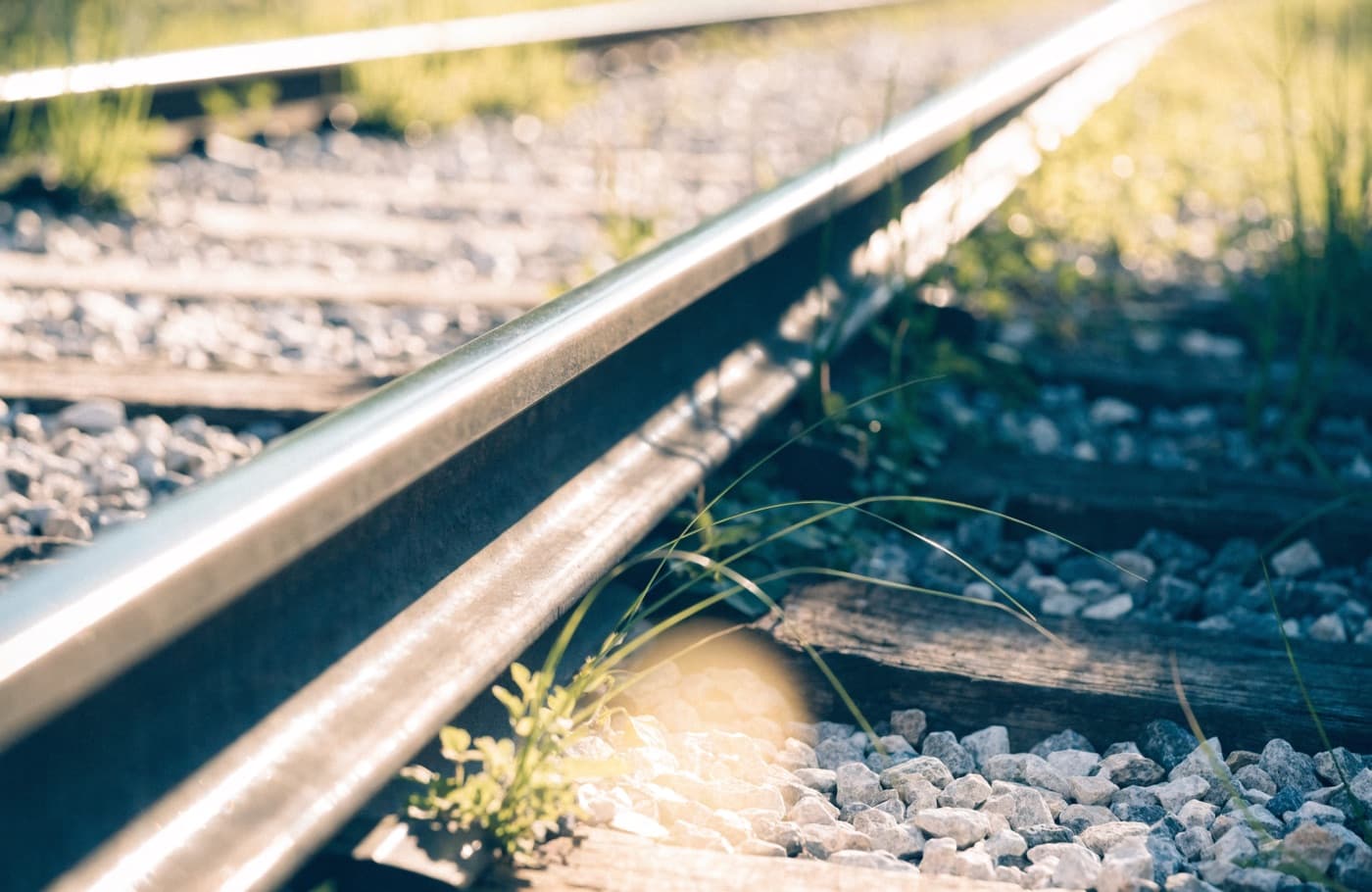 Close view of steel railway rail, sleepers and ballast in warm light